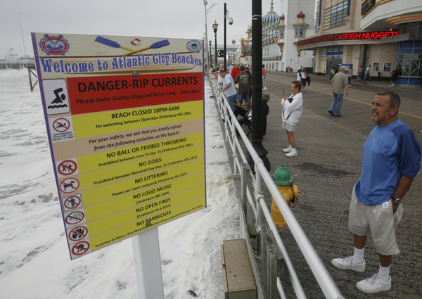 A storm watcher stands near the warning sign for swimmers on the boardwalk in Atlantic City, New Jersey, September 3, 2010. [Xinhua/Reuters]