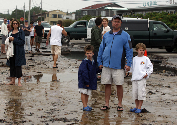 People stand in a flooded parking lot and look out to sea ahead of Hurricane Earl in Montauk, New York September 3, 2010. [Xinhua/Reuters]