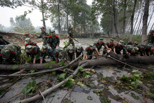 Soldiers clear fallen trees blocking a road in Luoyang on Sept 4. [Xinhua] 