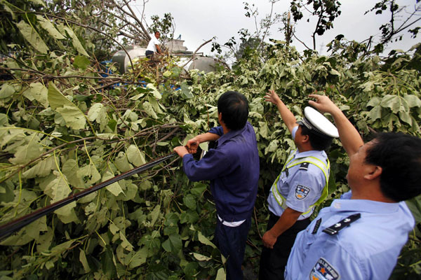 Traffic policemen guide a truck trapped by fallen branches in Luoyang on Sept 4. [Xinhua] 