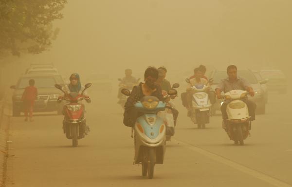 People drive motorcycles in sandstorm on a street in Kax, a city in northwest China&apos;s Xinjiang Uygur Autonomous Region, on Sept. 5, 2010. A heavy sandstorm hit Kax on Sunday, lowering the visibility to less than 100 meters in the city.