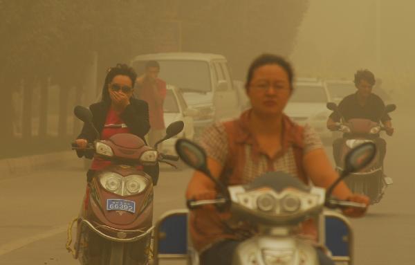 People drive motorcycles in sandstorm on a street in Kax, a city in northwest China&apos;s Xinjiang Uygur Autonomous Region, on Sept. 5, 2010. A heavy sandstorm hit Kax on Sunday, lowering the visibility to less than 100 meters in the city. 