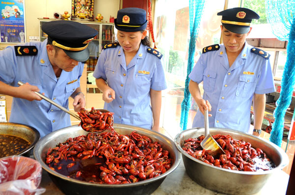 Market administrators in Lianyungang city, Jiangsu province, inspect the cooked crayfish in a local restaurant on Aug 25. [Wang Chun / for China Daily]