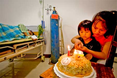 The sisters light candles on Li Yuanlei's 10th birthday cake in their mother's hospital room.