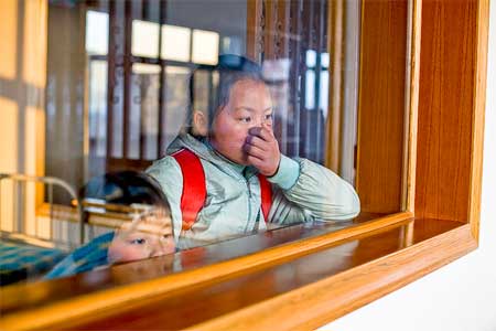 Li Qiaoli and her younger sister look at their mother from the ward's window.