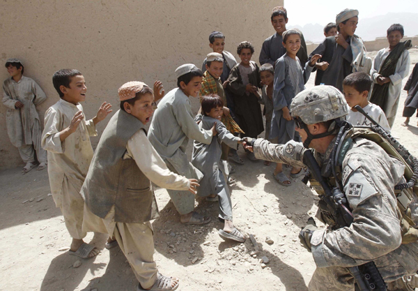 A U.S. soldier from Delta Company, a part of Task Force 1-66, plays with Afghani children at Arghandab river valley, Kandahar province, September 6, 2010. [Xinhua/Reuters]