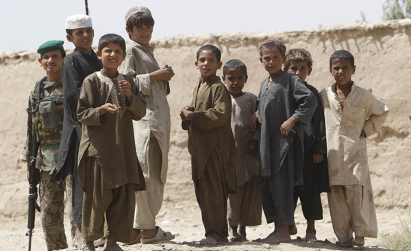 Afghan boys stand next to an Afghan army soldier at Arghandab river valley, Kandahar province, September 6, 2010. [Xinhua/Reuters]