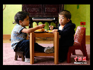 Edward Nino Hernandez (R) eats lunch with his eleven-year-old brother in their home in Bogota September 6, 2010. [Chinanews.com]