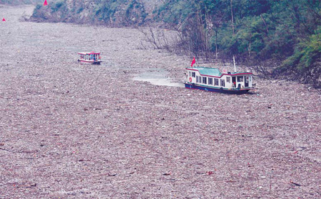 Passenger liners inch along on a lake formed by landslides in Beichuan, Sichuan province, on Sunday. Torrential rain has dumped tons of garbage and floating materials into the lake. [China Daily] 