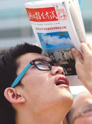 A student finds a more practical use for the National College Entrance Examination Guide as he shields himself from the sun at a college consultation fair in Wuhan, capital of Hubei province, in this file photo taken June 27. 