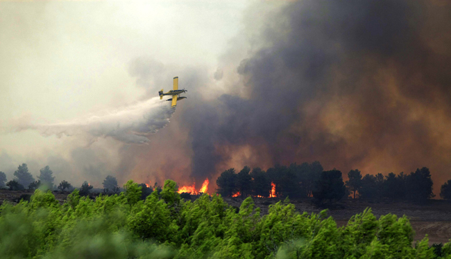 A fire-fighting plane dumps water over a forest fire in Spain&apos;s eastern Valencia region, September 7, 2010. The wildfires have ravaged some 2,000 hectares of land in Spain&apos;s eastern Valencia region, regional authorities said.[Xinhua/AFP]