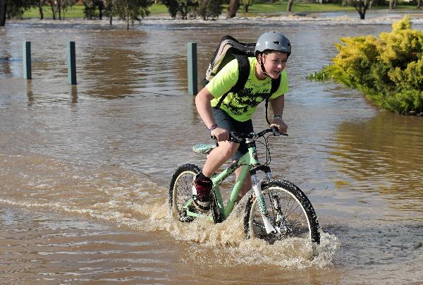 A boy rides his bike through the flood waters in Shepparton as floods hit the northern Victoria, some 200 kms north of Melbourne, September 7, 2010.