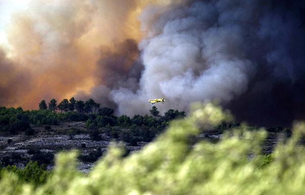 A fire-fighting plane dumps water over a forest fire in Spain&apos;s eastern Valencia region, September 7, 2010. The wildfires have ravaged some 2,000 hectares of land in Spain&apos;s eastern Valencia region, regional authorities said.