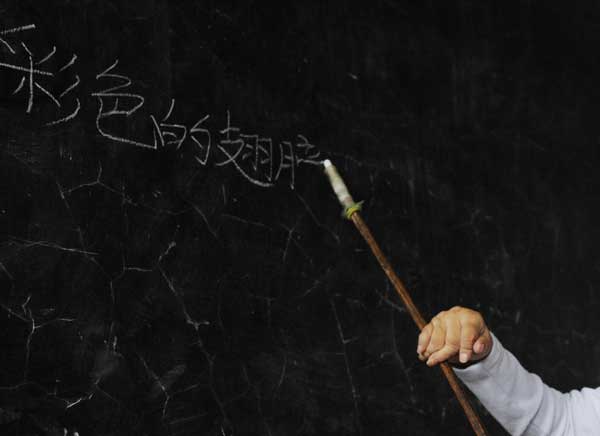 Ren Ying writes on the blackboard with a chalk extender, made by a tree branch and a syringe, as her hands have atrophied, Sept 7, 2010. 