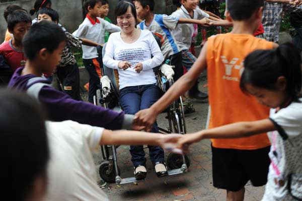 Students play games with Ren Ying, the teacher in a wheelchair, during their break, Sept 7, 2010. [Xinhua]