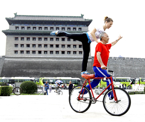 Yu Changqing, a man in his 70s, does bike stunts with his German friend at Deshengmen Square in Beijing on Sept 8, 2010.[Xinhua] 