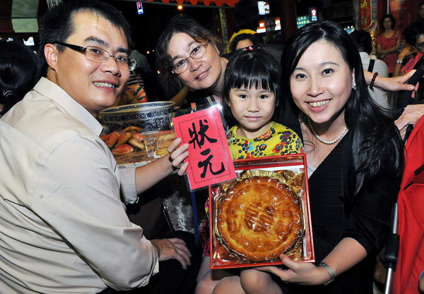 A family show their prize won at the Moon Cake Gambling Tournament in Kaohsiung in southwest Taiwan, Sept 8, 2010. [Xinhua]