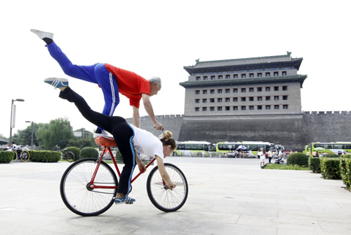 Yu Changqing, a man in his 70s, does bike stunts with his German friend at Deshengmen Square in Beijing on Sept 8, 2010. Yu has been doing bike stunts for more than 60 years, and the German woman manages a bike store in Beijing. [Photo/Xinhua]