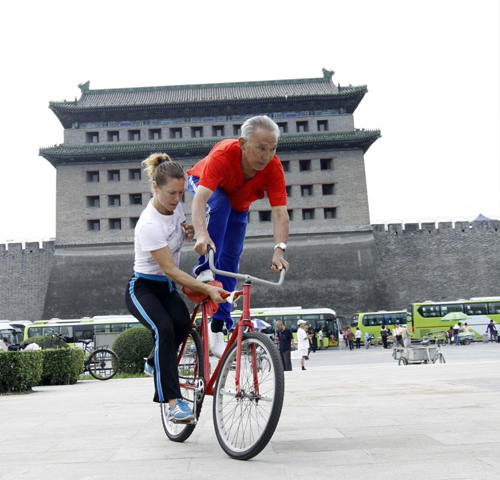 Yu Changqing, a man in his 70s, does bike stunts with his German friend at Deshengmen Square in Beijing on Sept 8, 2010. [Photo/Xinhua]