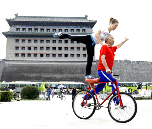 Yu Changqing, a man in his 70s, does bike stunts with his German friend at Deshengmen Square in Beijing on Sept 8, 2010.[Photo/Xinhua]