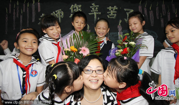 Students give their teacher a kiss to celebrate the upcoming Teacher&apos;s Day in Hongzhuan primary school in Chongqing, September 9, 2010. [CFP]