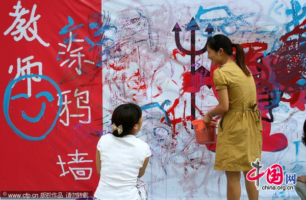 Teachers apply graffiti on a wall during an event to celebrate the upcoming Teachers' Day at an elementary school in Hanshan, East China's Anhui province, Sept 9, 2010. Teachers were organized to play games or receive psychological counseling to reduce their work pressure and celebrate the festival that falls on Sept 10. [CFP] 