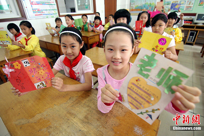 Students show cards which will give their teacher as a gift for upcoming Teacher's Day in Yixin primary school in Zhucheng, Shandong Province, September 9, 2010. [CFP]