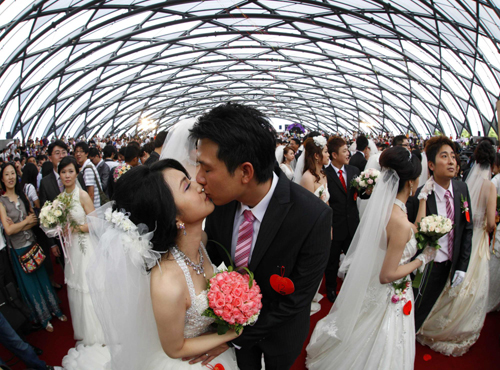 Zheng Ya-yuan (L), 32, and Chang Hong-chang, 31, who have been dating for six years, kiss during a mass wedding ceremony at the Taipei Flora Expo Hall Sept 9, 2010. [China Daily/Agencies]