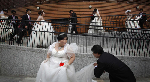 Zheng Ya-yuan (L), 32, and Chang Hong-chang, 31, who have been dating for six years, kiss during a mass wedding ceremony at the Taipei Flora Expo Hall Sept 9, 2010. [China Daily/Agencies]
