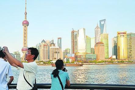 Visitors take pictures by the Huangpu River. 