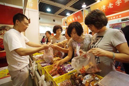 Visitors select and buy fried dough twist, a kind of Chinese traditional food at a stand of an enterprise during the 7th China Time-honored Brand Exposition held in Hangzhou, capital of east China's Zhejiang Province, Sept. 9, 2010. The 5-day exposition kicked off on Thursday, with the participation of nearly 200 time-honored enterprises across the country. [Xinhua photo]