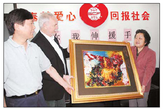 A foreign philanthropist (second from left) bought the embroidery work for 50,000 yuan, which was donated to Wenchuan quake victims. He later donated the work itself to the Shanghai Charity Foundation. The foundation's Director-General Chen Tiedi (right) received the painting.