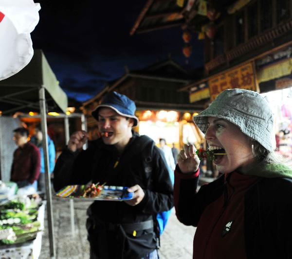 Two foreign tourists taste local food in Shangri-la County, Deqen Tibetan Autonomous Prefecture, southwest China's Yunnan Province, Sept. 11, 2010. A Kangba art festival will kick off here on Sunday. [Xinhua/Yang Zongyou]