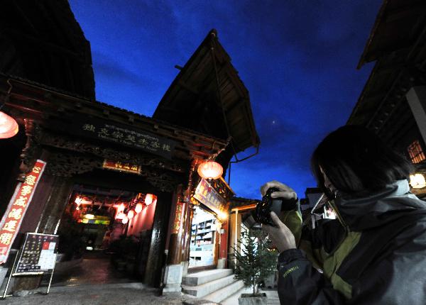 A tourist takes pictures in a street of Shangri-la County, Deqen Tibetan Autonomous Prefecture, southwest China's Yunnan Province, Sept. 11, 2010. A Kangba art festival will kick off here on Sunday. [Xinhua/Yang Zongyou]