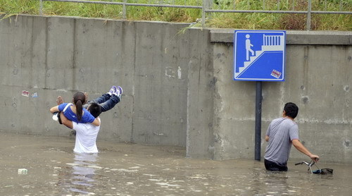  Local residents wade through a flooded street after heavy rains brought by tropical storm Meranti in Hangzhou, East China's Zhejiang province, Sept 12, 2010. [Xinhua]