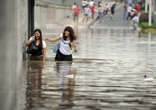 Local residents wade through a flooded street after heavy rains brought by tropical storm Meranti in Hangzhou, East China&apos;s Zhejiang province, Sept 12, 2010. [Xinhua]