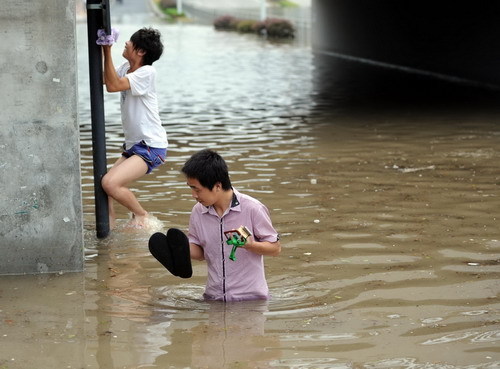 Local residents wade through a flooded street after heavy rains brought by tropical storm Meranti in Hangzhou, East China&apos;s Zhejiang province, Sept 12, 2010. [Xinhua]