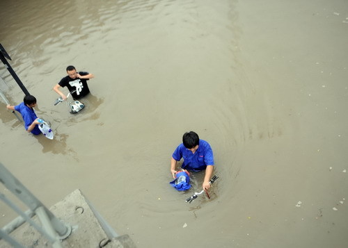 Local residents wade through a flooded street after heavy rains brought by tropical storm Meranti in Hangzhou, East China&apos;s Zhejiang province, Sept 12, 2010. [Xinhua]