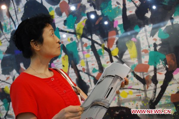 A visitor views paintings at the exhibition in honour of late Chinese artist Wu Guanzhong held in his hometown Yixing City, east China's Jiangsu Province, Sept. 12, 2010. The exhibition displayed 30 pieces of works of Wu, a master of Chinese paintings.