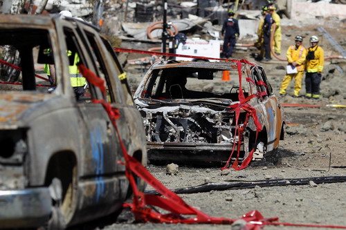 Emergency personnel look over the remains of burned vehicles along Glenview Drive near the site of a natural gas explosion in San Bruno, California September 11, 2010. [China Daily/Agencies]