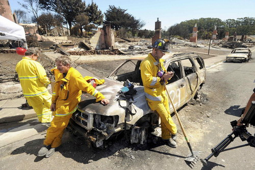 Emergency personnel lean against a burned out car at the site of a natural gas explosion in San Bruno, California September 11, 2010. [China Daily/Agencies]