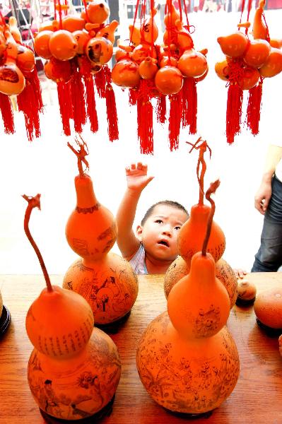 A child is attracted by various cucurbit artworks during the 4th cucurbit cultural festival in Liaocheng, east China's Shandong Province, Sept. 12, 2010. More than 50 creative cucurbit manufacture orders, with a total value of 3.2 million RMB yuan, were signed in the 3-day festival. [Xinhua photo]