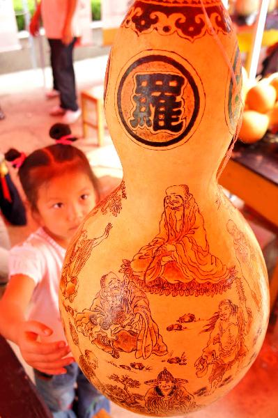 A girl is attracted by a cucurbit artwork during the 4th cucurbit cultural festival in Liaocheng, east China's Shandong Province, Sept. 12, 2010. More than 50 creative cucurbit manufacture orders, with a total value of 3.2 million RMB yuan, were signed in the 3-day festival. [Xinhua photo]