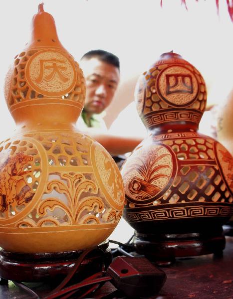 A merchant views a cucurbit light during the 4th cucurbit cultural festival in Liaocheng, east China's Shandong Province, Sept. 12, 2010. More than 50 creative cucurbit manufacture orders, with a total value of 3.2 million RMB yuan, were signed in the 3-day festival. [Xinhua photo]