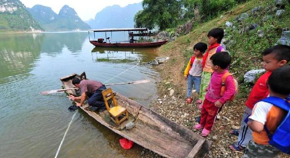 Shi Lansong gets water out of a wooden boat before taking his students to school in South China's Guangxi Zhuang autonomous region on Sept 6, 2010.