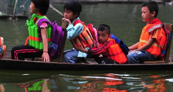 Students sit on the wooden boat on their way to school in South China's Guangxi Zhuang autonomous region on Sept 7, 2010. 