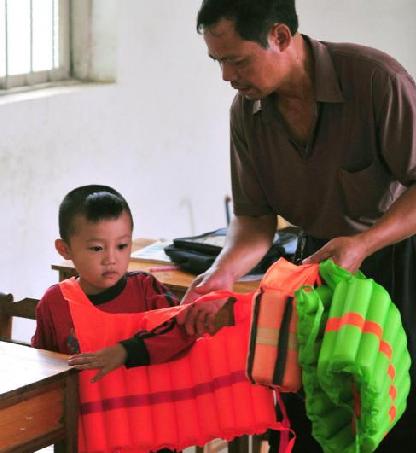 Shi helps a student out of his life jacket before class in South China's Guangxi Zhuang autonomous region on Sept 7, 2010.