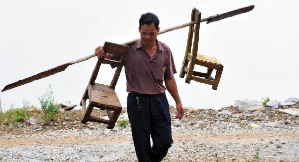 Shi carries two stools using an oar after sending his students home in South China's Guangxi Zhuang autonomous region on Sept 6, 2010.