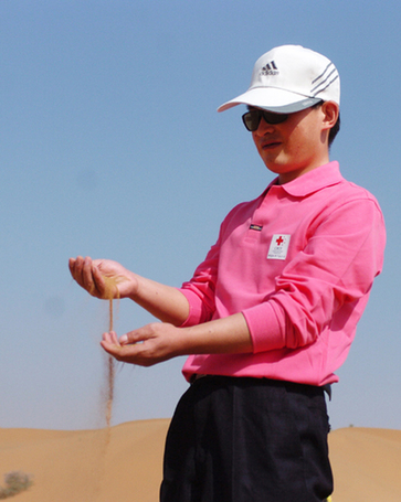 A visually impaired man feels the desert sand through his hands in northwest China&apos;s Ningxia Hui autonomous region on Sept 13, 2010. [Xinhua]