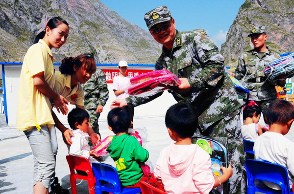 Soldiers from Lanzhou military command who assisted in the construction of the makeshift kindergarten bring school supplies to kids in Zhouqu, Gansu province on September 14, 2010. [Photo/Xinhua]